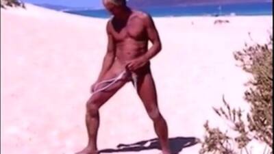 Tanned guy on beach in tiny string thong (temporarily!) on youpornvideos.one